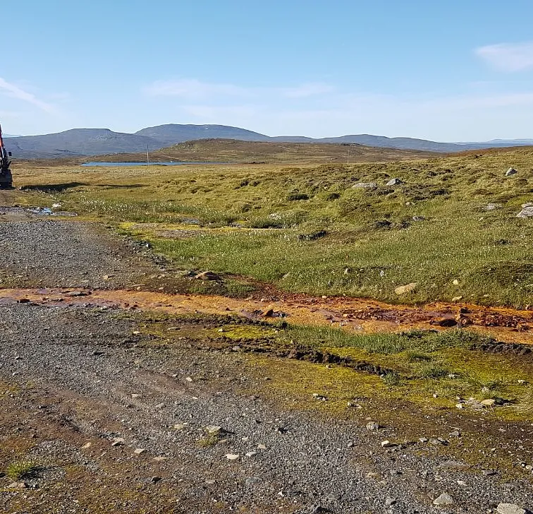 Gravemaskin på grusvei i fjellområde
