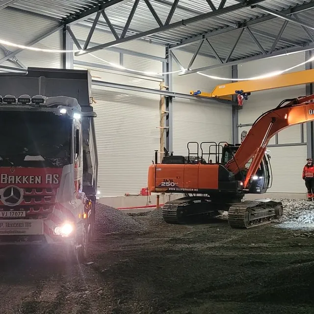 Gravemaskin og lastebil i hall