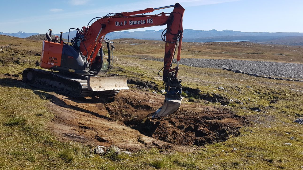 Gravemaskin i arbeid i fjellområde