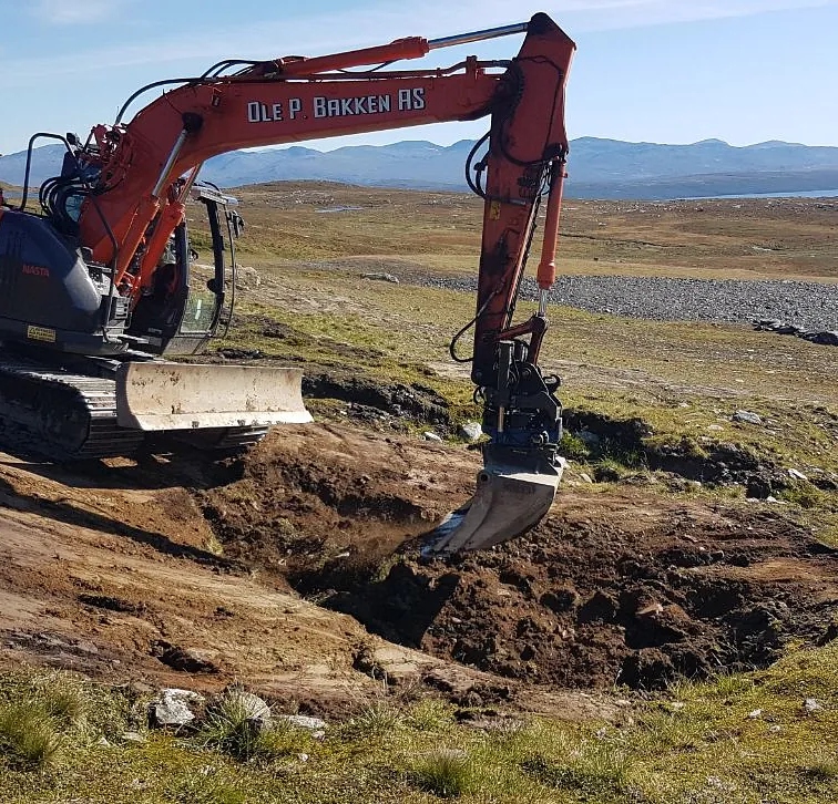 Gravemaskin i arbeid i fjellområde
